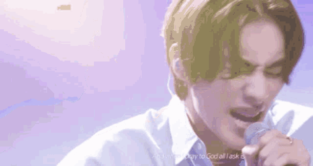 a young man is singing into a microphone while wearing headphones .