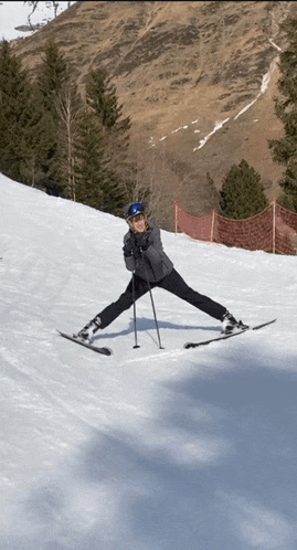 a person is skiing down a snow covered slope with trees in the background