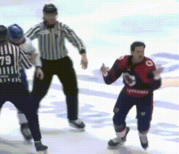 two ice hockey players are fighting on the ice while a referee looks on .