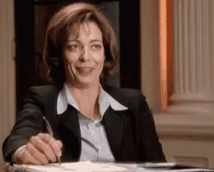 a woman in a suit is sitting at a desk with a pen in her hand .
