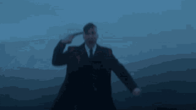 a man in a suit is pointing a gun at his head .
