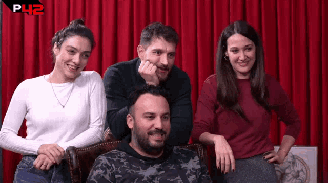 a group of people sitting in front of a red curtain with the letters p42 on the bottom right