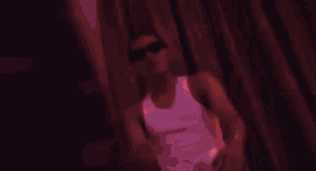 a man in a white tank top is sitting in front of a red curtain .