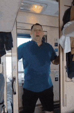a man in a blue shirt and black shorts is standing in a train