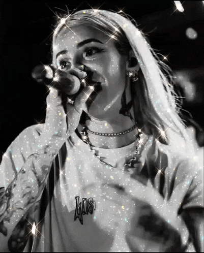a black and white photo of a woman singing into a microphone .