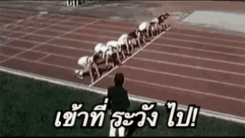 a group of runners are getting ready to run on a track and a man is watching .