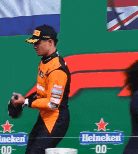 a man standing in front of a green wall with heineken signs on it