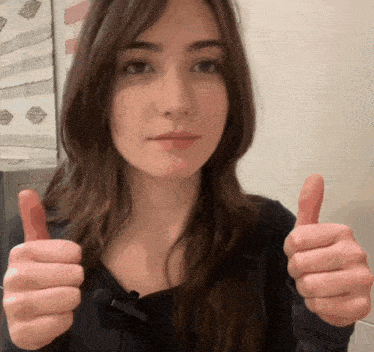 a woman giving a thumbs up with a microphone on her neck