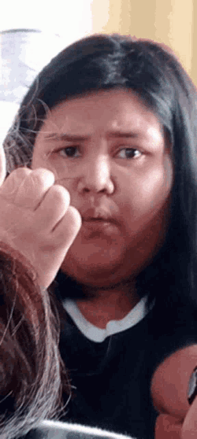 a woman making a funny face with her fist in front of her face