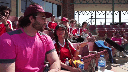 a group of people are sitting in a stadium with a bottle of aquafina water