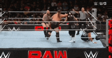 a group of men are wrestling in a wrestling ring while a referee watches .
