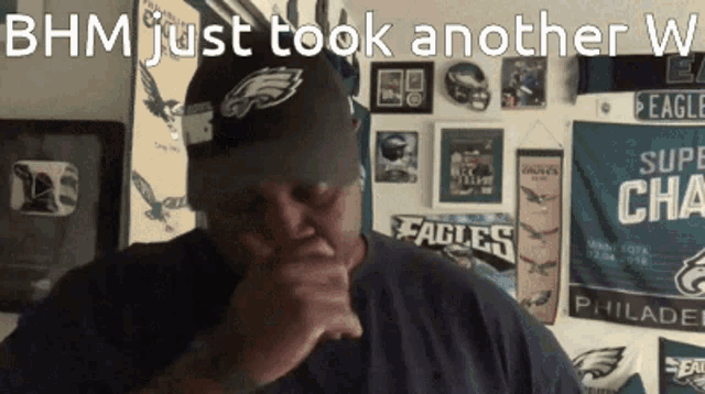 a man wearing a philadelphia eagles hat stands in front of a wall with eagles signs