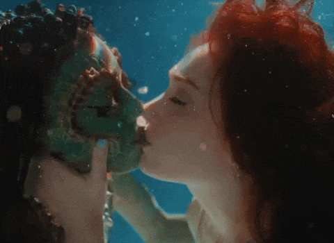a man and a woman kissing underwater with their faces painted green