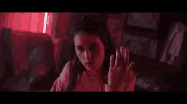 a woman is sitting on a couch in a dark room with red lights