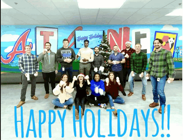 a group of people standing in front of a wall that says happy holidays on it