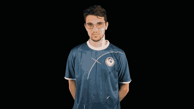 a man wearing glasses and a blue shirt with a circle on the front