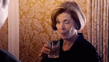 a woman is holding a glass of water in front of a curtain .