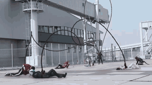 a group of people laying on the ground in front of a fence