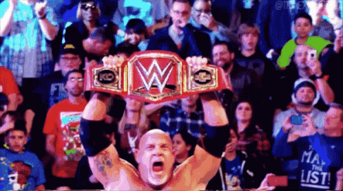 a man is holding a wrestling championship belt in front of a crowd