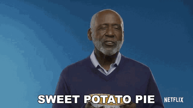 a man in a purple sweater is holding a potato pie and says sweet potato pie