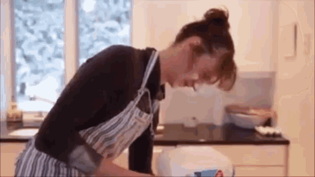 a woman in an apron is standing in front of a blender