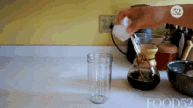 a person pouring liquid into a glass with the number 52 on the bottom