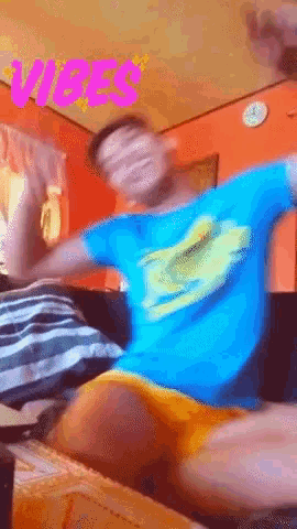 a man in a blue shirt is sitting on a couch with the word vibes in pink letters