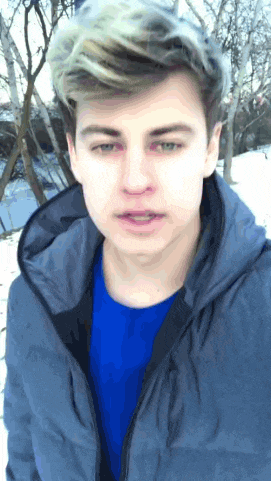 a young man wearing a blue shirt and a gray jacket