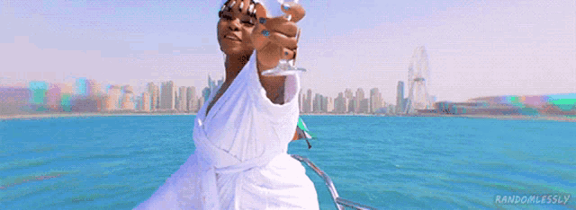 a woman in a bathrobe is holding a glass of wine while standing on a boat in the ocean .