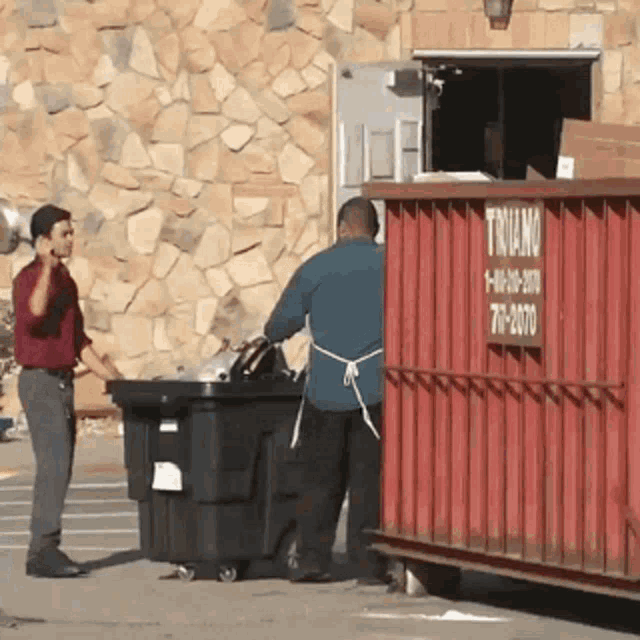 a man talking on a cell phone next to a trash can that says triano on it