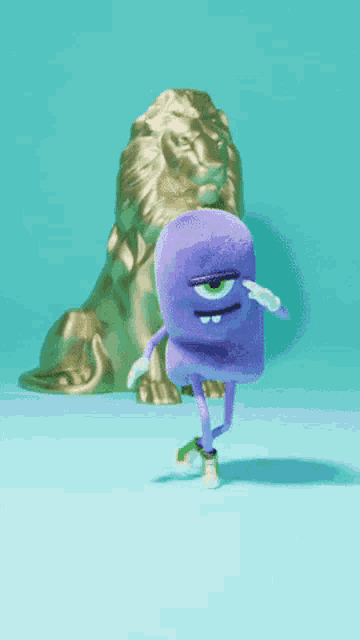 a purple stuffed animal is standing in front of a gold lion statue