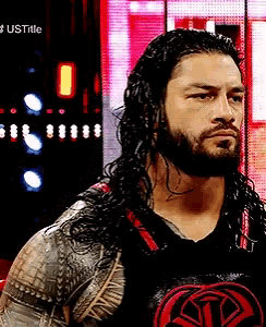a man with long hair and a beard is wearing a black shirt with a red logo on it