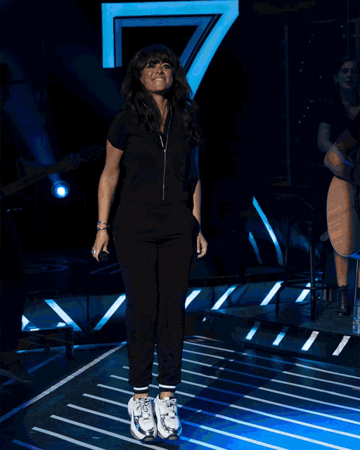 a woman in a black jumpsuit is dancing on a stage