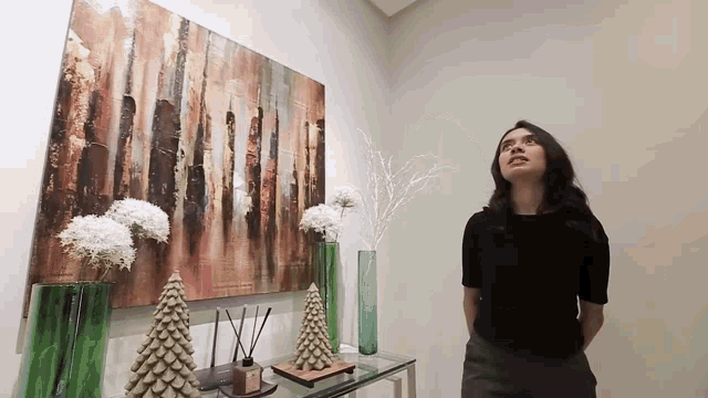 a woman is standing in front of a large painting on the wall