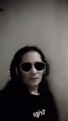 a woman wearing sunglasses and headphones is wearing a black shirt that says ' ogi ' on it