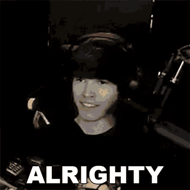 a man wearing headphones is smiling in front of a microphone with the word alrighty written on the bottom