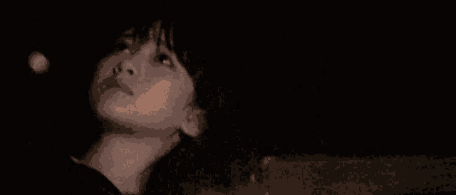 a close up of a person 's face in the dark looking up .
