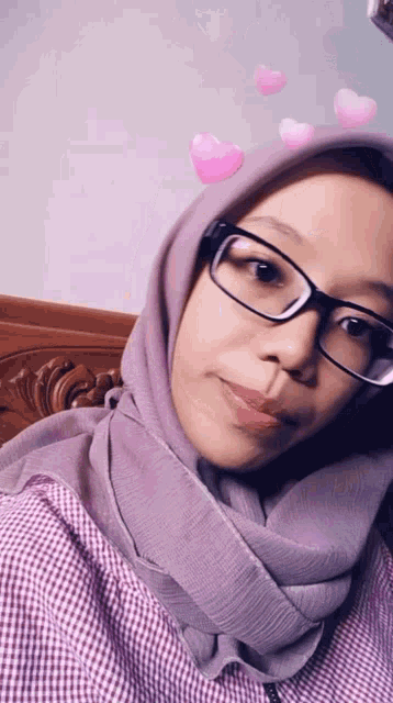 a woman wearing glasses and a purple hijab with pink hearts on her face