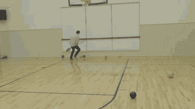 a man walking on a basketball court with balls on the floor