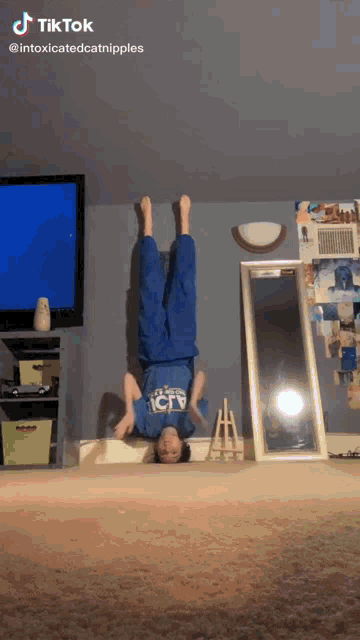 a person doing a handstand in front of a tv and a mirror
