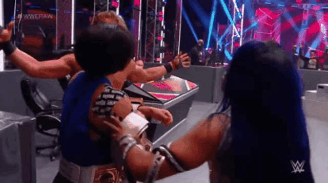 a group of wrestlers are hugging each other on a wrestling stage .