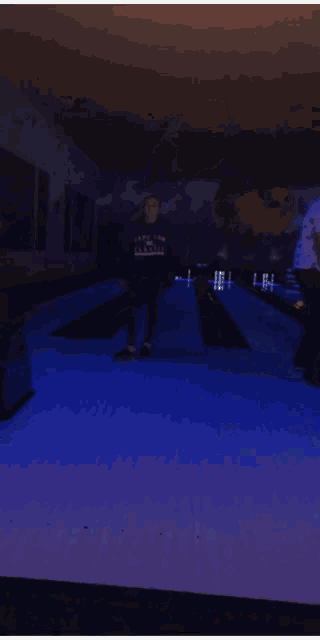 a man wearing a sweatshirt that says ape on it is standing in a bowling alley