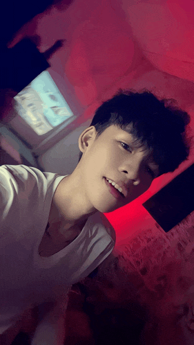 a young man taking a selfie in front of a red background