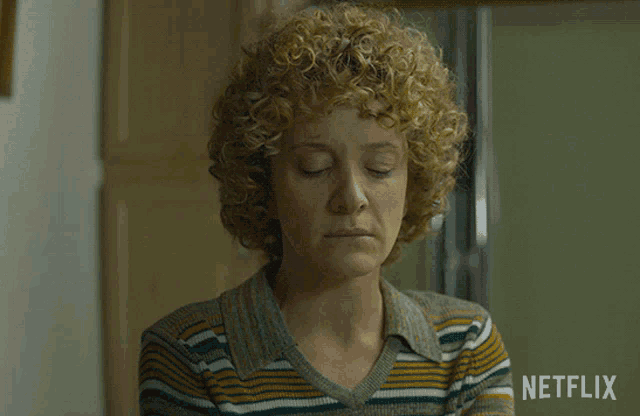 a woman with curly hair is wearing a striped shirt with a netflix logo on the bottom