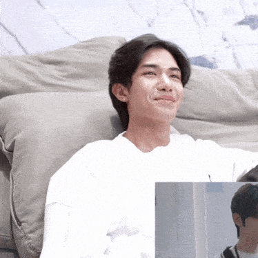a man in a white shirt sits on a grey couch