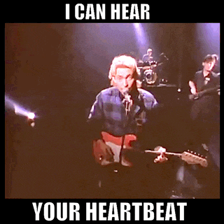 a man singing into a microphone with the words i can hear your heartbeat underneath him