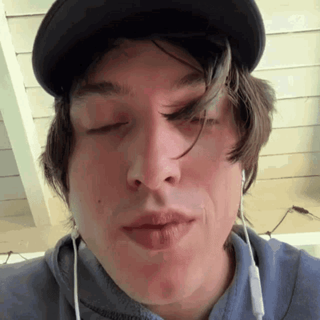 a close up of a man wearing a hat and earbuds