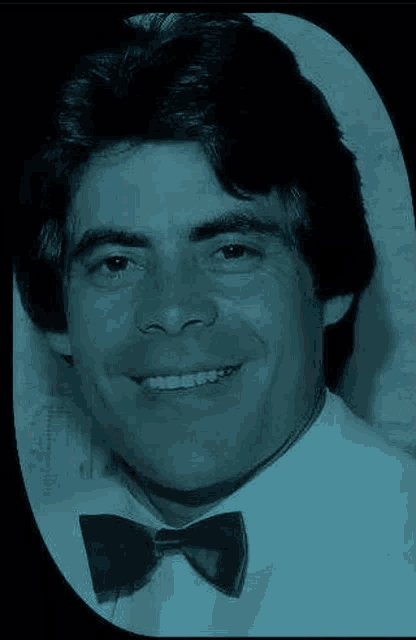 a man in a tuxedo and bow tie is smiling for the camera .