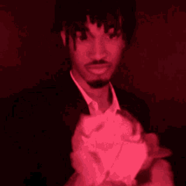 a man in a suit and tie is holding a pink object in his hand .