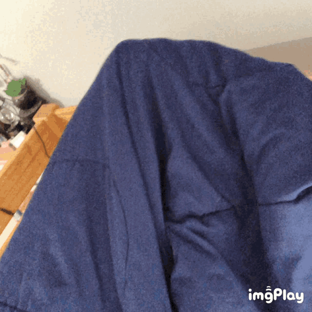 a blue blanket is laying on a bed next to a imgplay icon